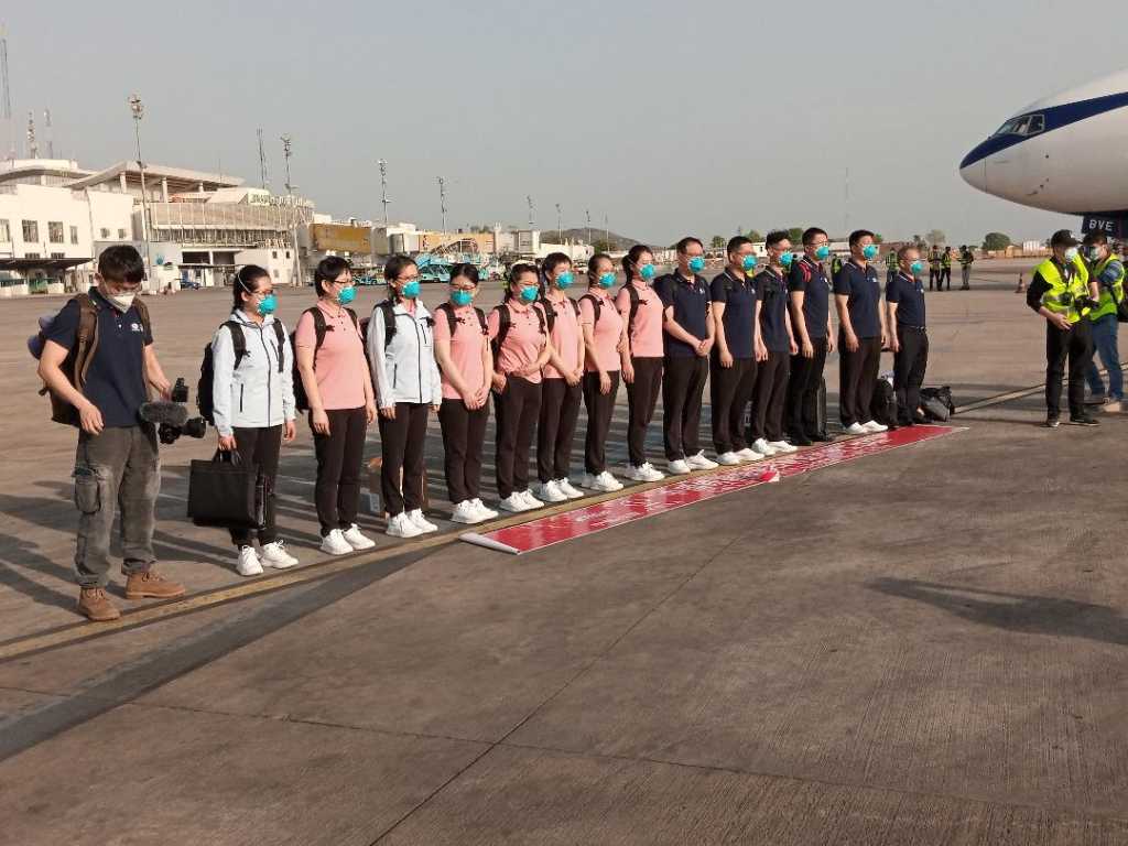 Chinese medics stand on the tarmac at the Nnamdi Azikwe International Airport in Abuja, on April 8, 2020 as they arrived in Nigeria to help fight the coronavirus pandemic, despite angry criticism from health workers in the west African nation. - The 15-strong team were greeted by senior officials on the tarmac at Abuja airport after flying in on a month-long deployment with a planeload of medical supplies. (Photo by Kola Sulaimon / AFP)